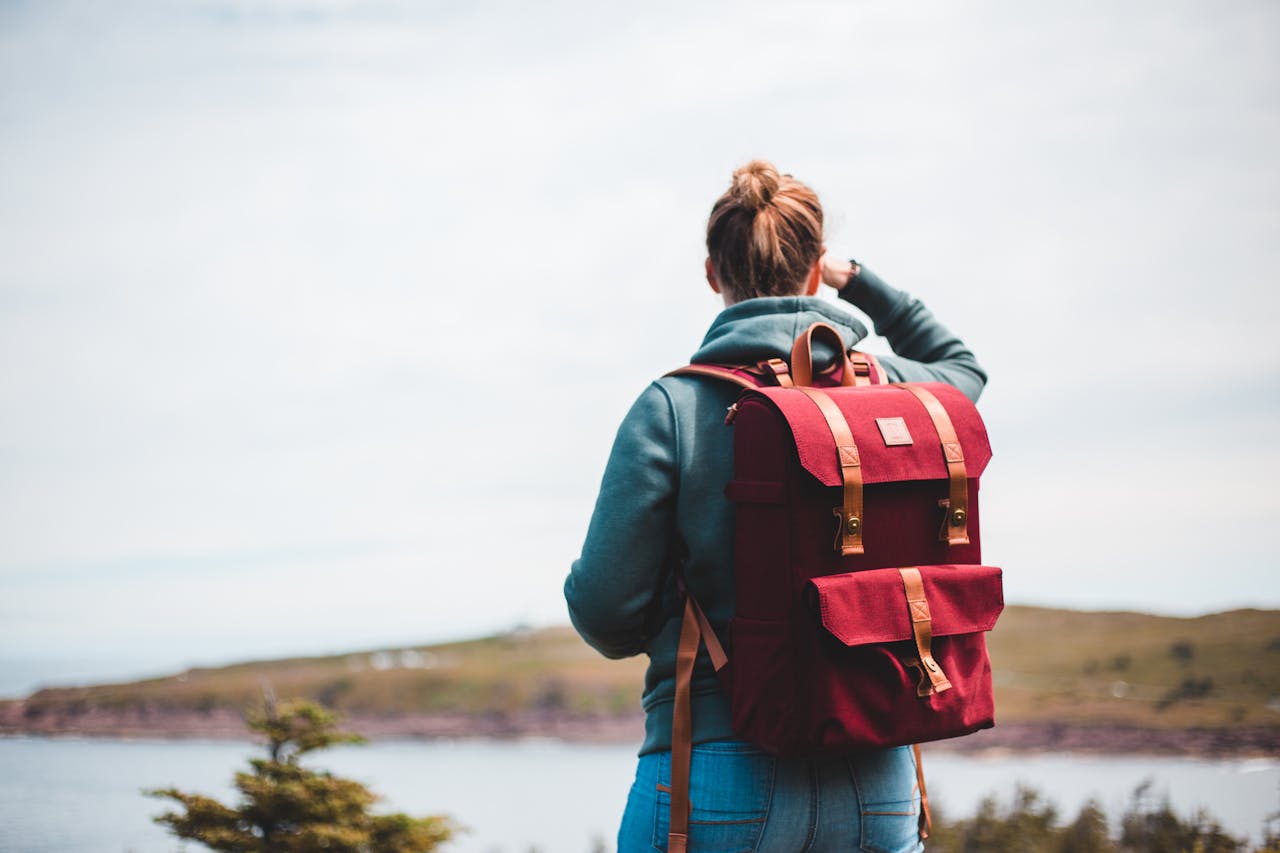 Woman with a backpack looking at the scenic landscape surrounding a lake, embodying a spirit of adventure.